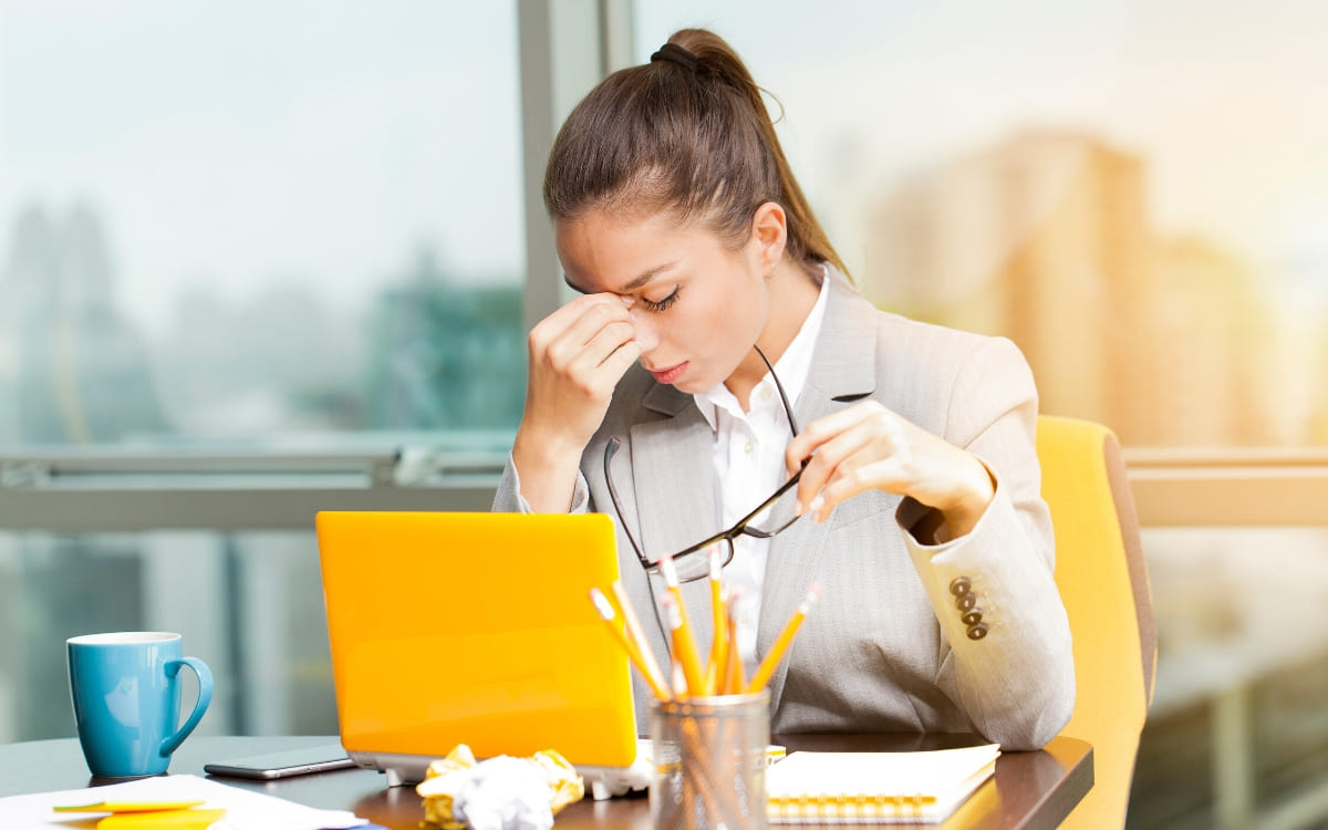 A stressed woman working in front of a yellow computer