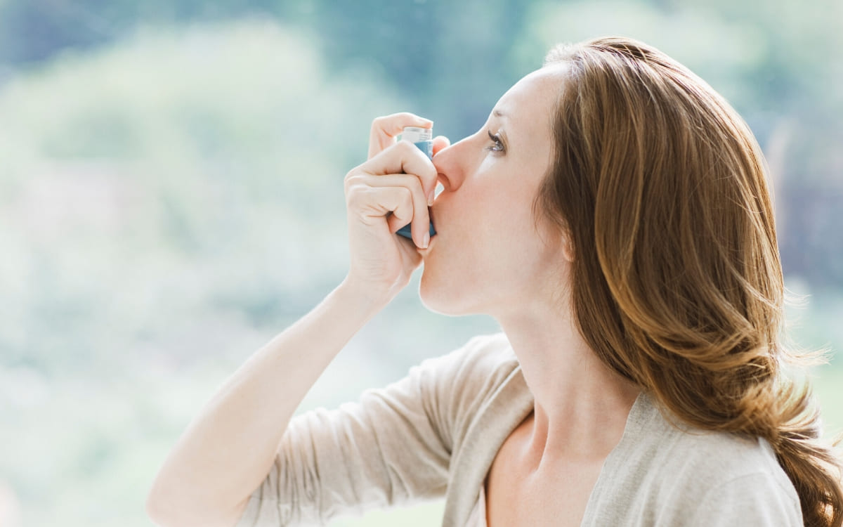 A woman suffering from asthma breathing from an inhaler