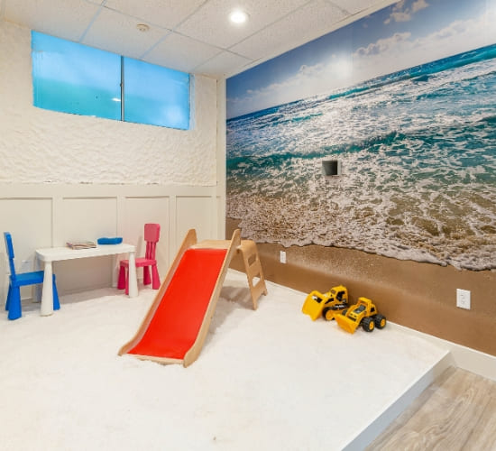 The children's room at the salt room orlando featuring a slide and playing area with a relaxing background of the ocean