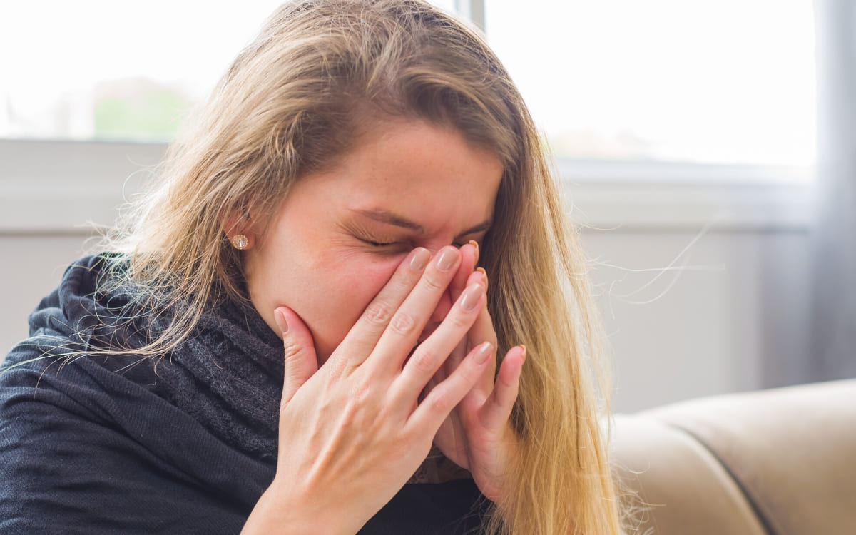 A woman with rhinitis trying to breathe as she tries to open up her stuffed nose