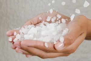 A woman's hands holding salt as it is being poured on her hands