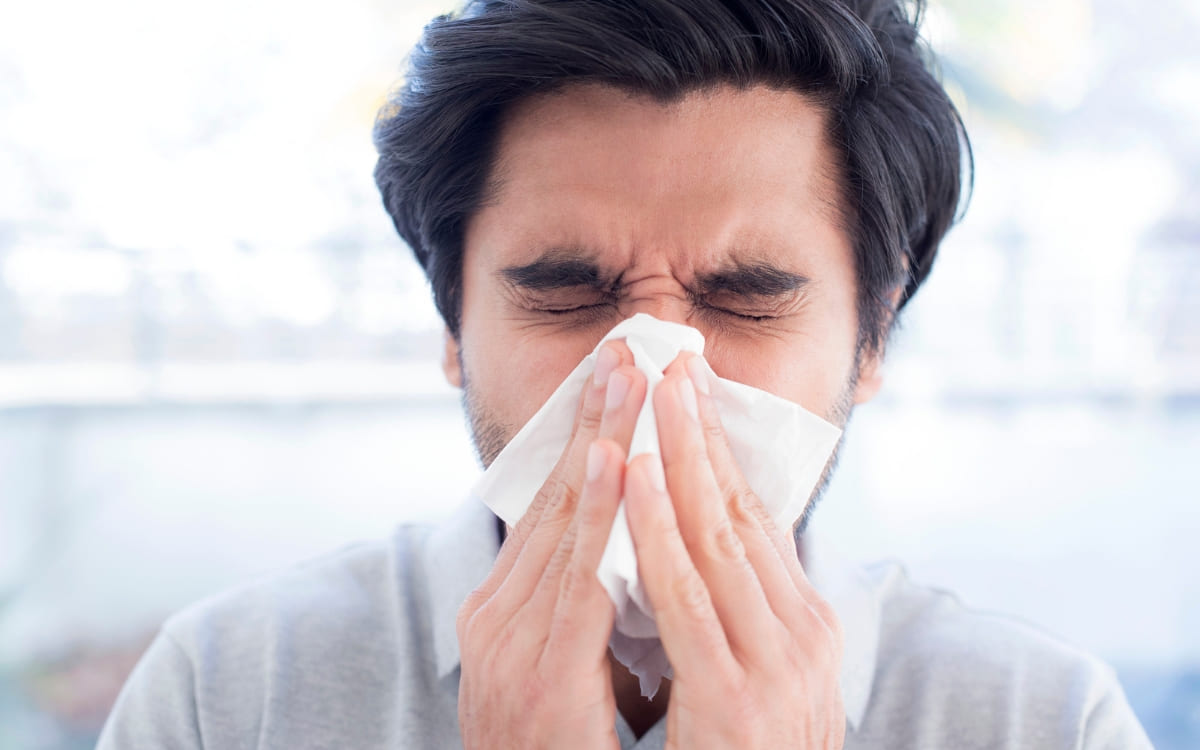 A man with sinusitis blowing his nose into a napkin