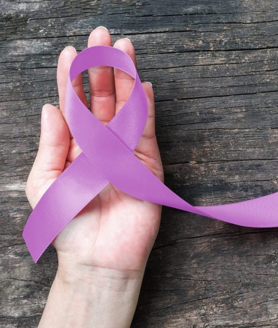 The hand of a woman holding a purple ribbon representing colon issues
